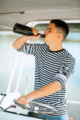 A young and handsome Caucasian man sailing in the sea on a boat on a sunny day.