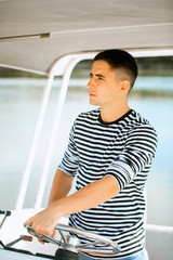 A young and handsome Caucasian man sailing in the sea on a boat on a sunny day.