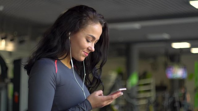 Young girl with headphones using a smartphone on an exercise bike
