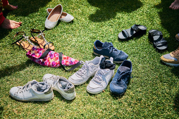 A bunch of pairs of shoes and shoes from different people on the green lawn