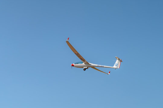 Motorglider LAK-17 Mini FES OH-1032 with Front Electric selflauncher powered by electrical motor and small and foldable propeller is flying in a cloudless blue sky. Kotka, Finland.