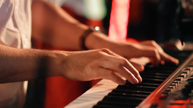 The hands of a musician closeup playing the synthesizer on a rock concert.