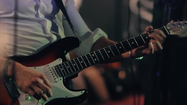 Male musician plays bass guitar at a rock concert.