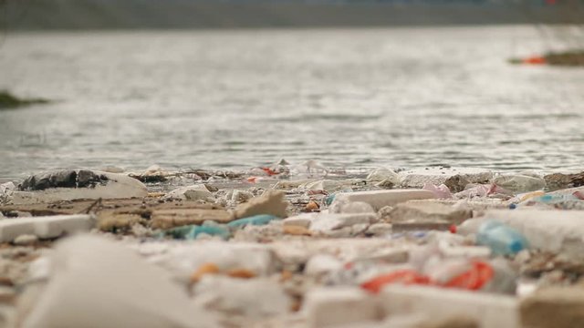 Garbage floats in the water near the shore. Environmental pollution.