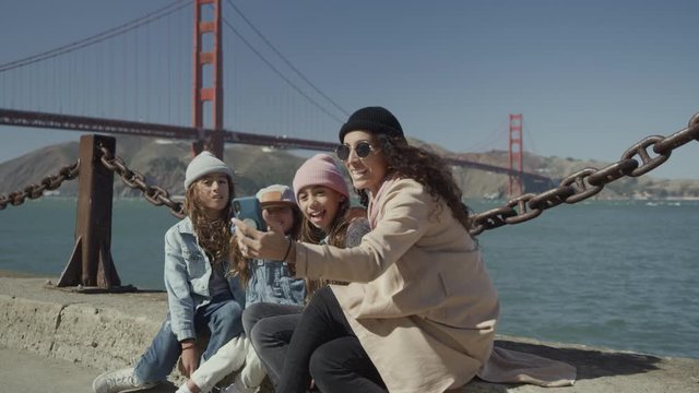 Mother and children posing for cell phone selfie near Golden Gate Bridge / San Francisco, California, United States