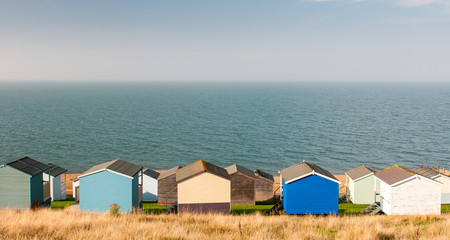 Colourful holiday wooden beach huts facing the  sea. - obrazy, fototapety, plakaty