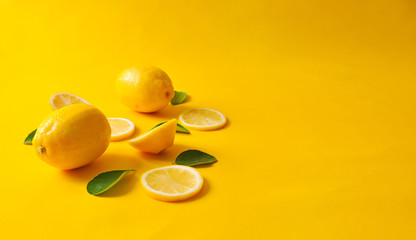 Lemons and green leaves on bright yellow background. Food concept, flat lay. Lemon fruit, citrus minimal concept, vitamin C. Creative background made of lemon and leaf.