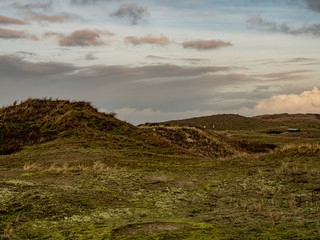 Norderney, Germany. 7 December 2019. Grassy dunee under cloudy sky on the island of Norderney in...