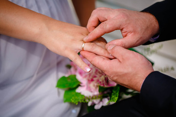 Obraz na płótnie Canvas Groom putting wedding ring on bride's finger during the wedding ceremony 