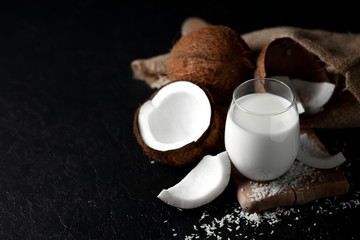 fresh coconut milk in a glass against a dark background, coconut cosmetic cream, milkshake with coconut slices