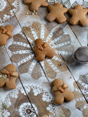 Gingerbread cookies with honey holding salted almond on wooden table with white powdered sugar sprinkled all over in shape of snow flakes. Rustic and delicate perfect for Christmas time and holidays.