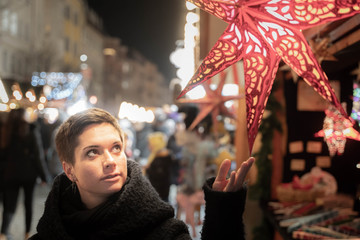 Portrait of a young woman on a christmas market in Germany looking at a christmas star