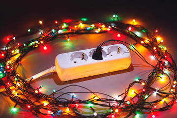 Christmas garland lights circle around electric extension cord