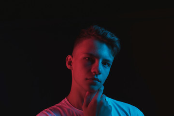 Slender young guy posing in neon red and blue light