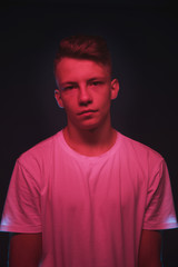 Fototapeta premium Slender young guy posing in neon red and blue light