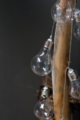 New Year or Christmas background, close-up of garland of light bulbs on a dry wooden branch, selective focus