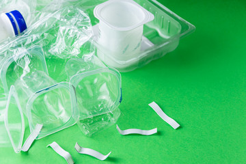 Top view of plastic containers on green background, ready for recycling, horizontally with copy space