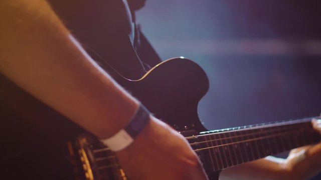 Close up pano rock musician with guitar appears in smoke scene. Slow motion playing on stage