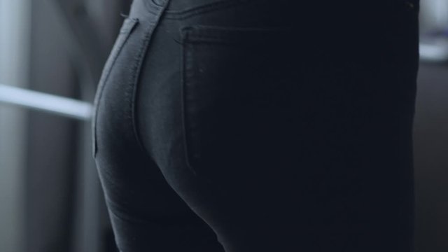 The slender girl wears jeans on ass in Lacy underwear. Sexy female wearing a of pants. Seductive woman standing with her back to the camera and shows a beautiful ass, butt.