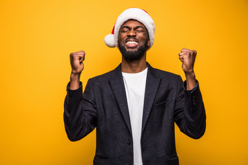 Happy winner. New year sale. Happy smiling black african american man in christmas hat isolated on yellow background.