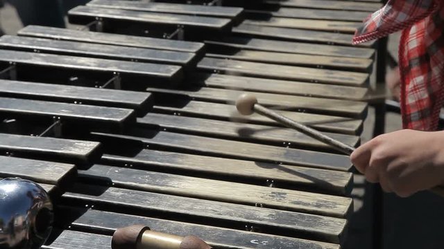 A street musician plays with chopsticks on a metallophone