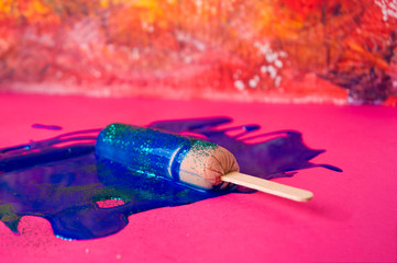 Sausage on sticks in blue sparkle paint. On a pink and orange textured background, top view photo.