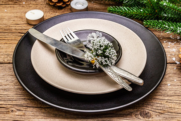 Christmas and New Year dinner place setting. Evergreen fir tree branch, candles, cones, ceramic...