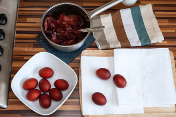 Easter eggs dyed in natural way placed on kitchen paper towel and in white bowl.