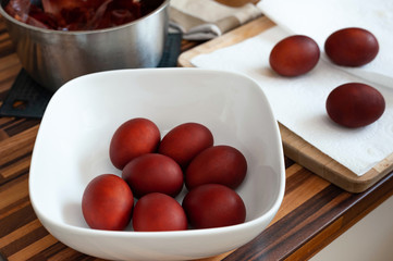 Easter eggs dyed in natural way placed on kitchen paper towel and in white bowl.