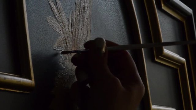 painter decorator draws a pattern of birds, close-up, silhouette at dusk