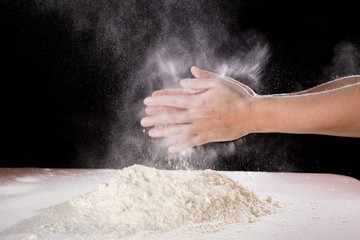 chef's hand clapping with powder flour when kneading the dough
