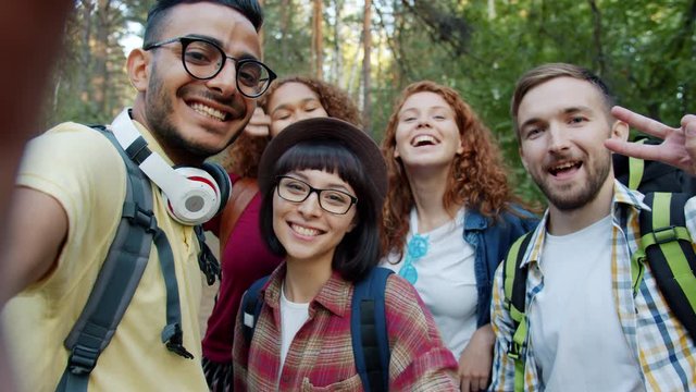 POV of happy friends multi-racial group taking selfie in forest posing with hand gestures having fun together. Modern lifestyle, friendship and nature concept.