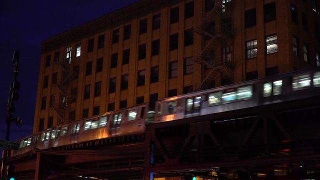 Night time exterior establishing shot of generic Chicago apartment building expensive real estate lofts as L train passes by on overhead tracks outside NX