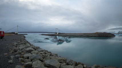 Iceberg floats in the water close to bridge next to diamond beach and Jokulsarlon glacier lagoon