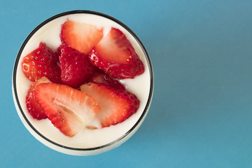 Aerial photograph of yogurt with chopped strawberry and blue background
