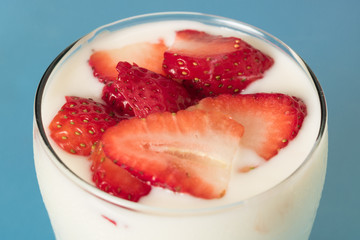 Aerial photograph of yogurt with chopped strawberry and blue background