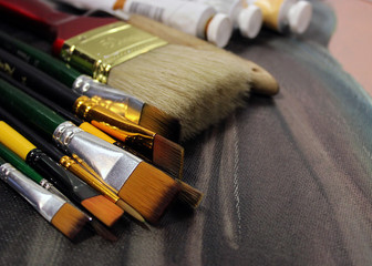 Brushes and oil paints on canvas Clean brushes of different shapes and sizes. Tubes with oil paint...