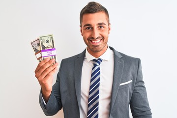 Young handsome business man holding bunch of dollars banknotes over isolated background with a happy face standing and smiling with a confident smile showing teeth