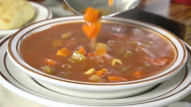 Spooning meatball soup into a bowl slow motion