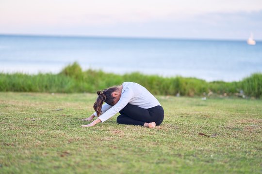 Young beautiful sportwoman practicing yoga. Coach teaching postures at park