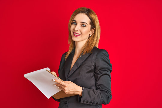 Young beautiful redhead businesswoman wearing suit writing on flip board