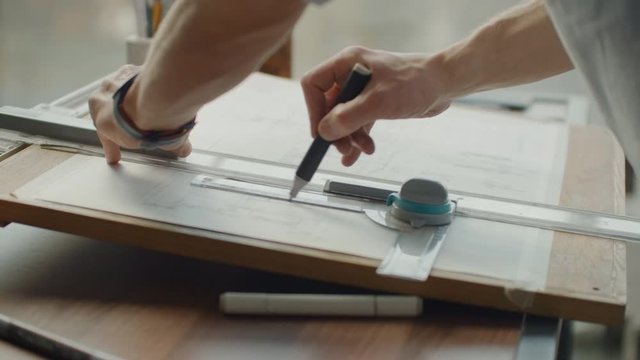 A male architect creates a drawing of a building on paper. To study the design of premises, to create furniture and houses. Large modern office draw on blackboard