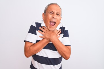 Senior grey-haired man wearing casual striped polo standing over isolated white background shouting and suffocate because painful strangle. Health problem. Asphyxiate and suicide concept.