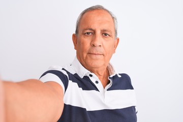 Senior grey-haired man wearing striped polo make selfie over isolated white background with a...