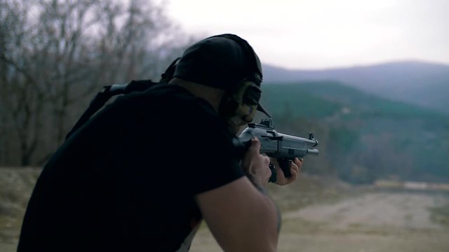 Shooter with a pump-action shotgun shoots a target at a sports tactical training ground, slow motion