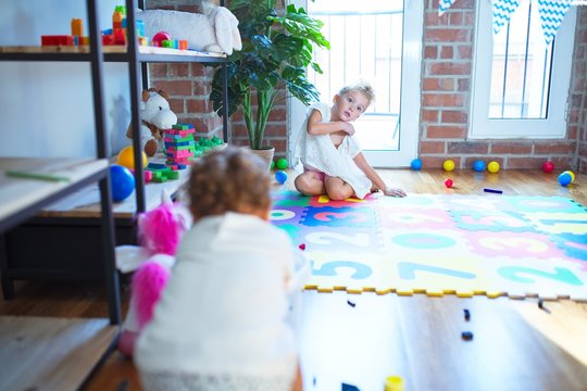 Beautiful toddlers playing around lots of toys at kindergarten