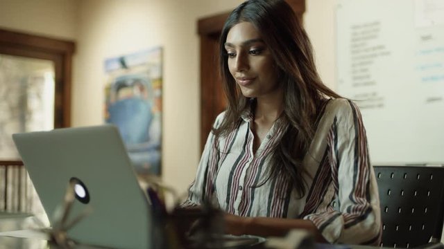 Woman holding paper rolling on office chair then typing on laptop / Cedar Hills, Utah, United States