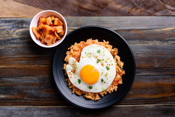 Kimchi fried rice with fried egg and radish kimchi on wooden background, Korean food