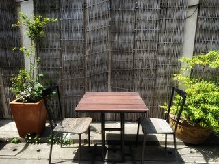 The table and the empty chairs are located on the side of the wall and plant pots on the side.