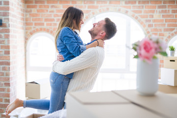 Young beautiful couple hugging at new home around cardboard boxes